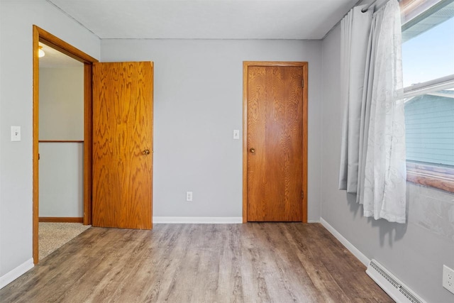 1416 21st Ave S, Wisconsin Rapids, WI 54495 - unfurnished bedroom featuring wood finished floors, a baseboard radiator, and baseboards