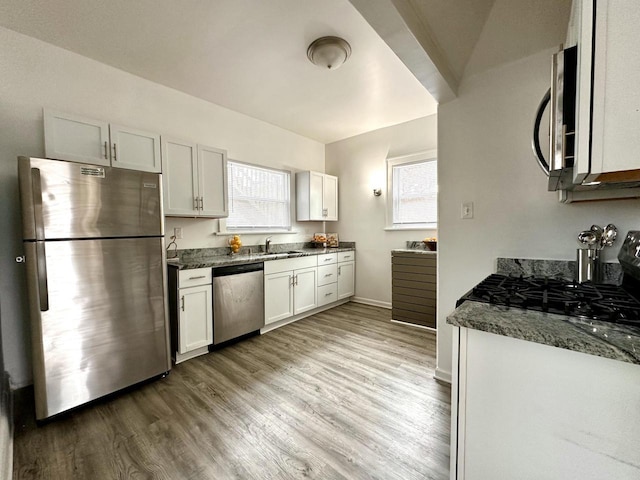 4416 75th St, Kenosha, WI 53142 - kitchen with stainless steel appliances, a sink, light wood-type flooring, dark stone counters, and white cabinetry