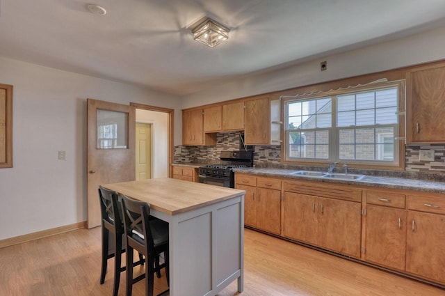 167 Po St, West Bend, WI 53090 - kitchen featuring black range with gas cooktop, backsplash, a sink, and light wood finished floors
