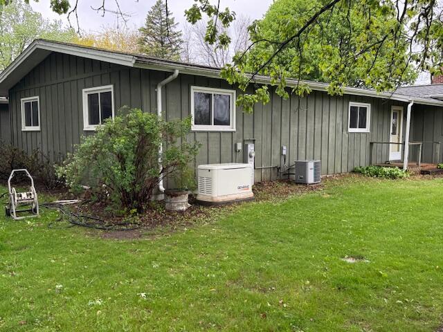 W6782 Marine Dr, Markesan, WI 53946 - view of property exterior with board and batten siding, a lawn, and central AC