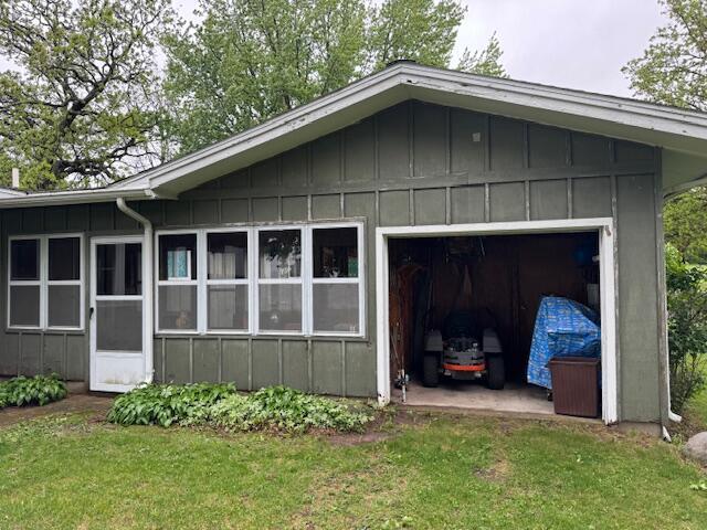 W6782 Marine Dr, Markesan, WI 53946 - view of side of property with board and batten siding, a garage, driveway, and a lawn