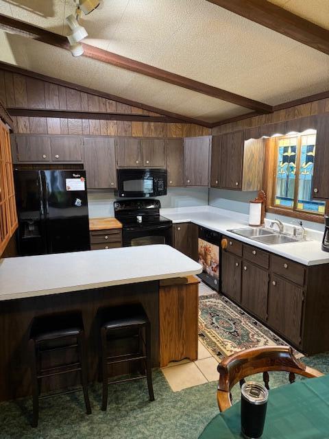 W6782 Marine Dr, Markesan, WI 53946 - kitchen with black appliances, wooden walls, light countertops, a sink, and a breakfast bar area