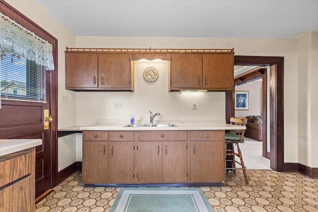 611 Highland Ave, Kewaskum, WI 53040 - kitchen featuring light countertops, a sink, baseboards, and a breakfast bar