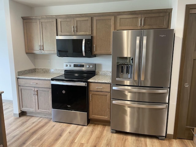 412 Emerald Ct, Kewaskum, WI 53040 - kitchen with appliances with stainless steel finishes, light wood-type flooring, and light stone counters