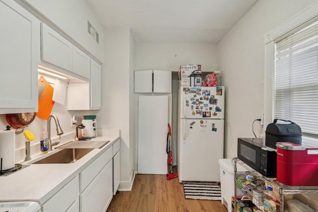 2202 N 55th St, Milwaukee, WI 53208 - kitchen featuring freestanding refrigerator, a sink, light wood finished floors, and white cabinetry