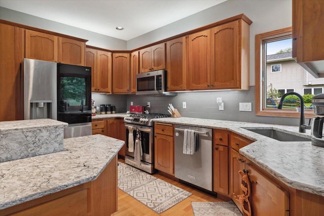 405 August Hills Dr, La Crescent, MN 55947 - kitchen featuring appliances with stainless steel finishes, a sink, light wood-style flooring, light stone countertops, and decorative backsplash