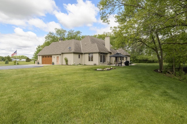 W360S9910 Markham Rd, Eagle, WI 53119 - rear view of house featuring a gazebo, driveway, a garage, a lawn, and a chimney