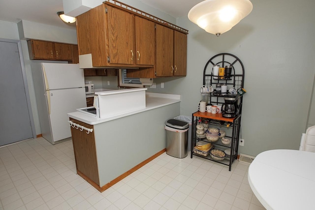 2373 S 83rd St, West Allis, WI 53219 - kitchen featuring white appliances, light countertops, brown cabinets, a peninsula, and baseboards