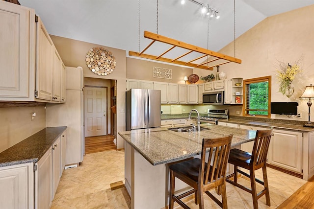 2511 S Natures Ridge Rd, Beloit, WI 53511 - kitchen with appliances with stainless steel finishes, a sink, high vaulted ceiling, a kitchen island with sink, and dark stone countertops