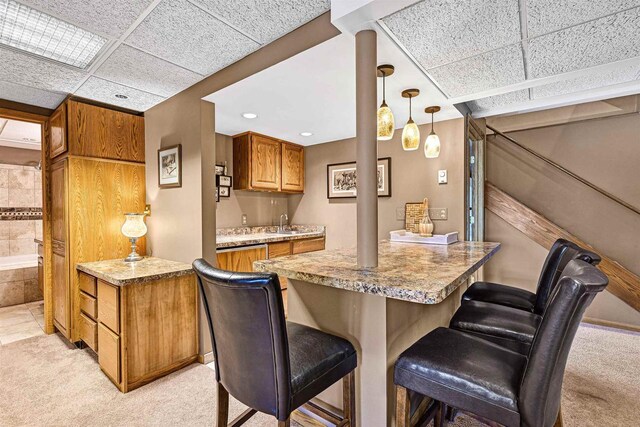 2511 S Natures Ridge Rd, Beloit, WI 53511 - kitchen featuring light carpet, a kitchen breakfast bar, brown cabinets, a peninsula, and pendant lighting