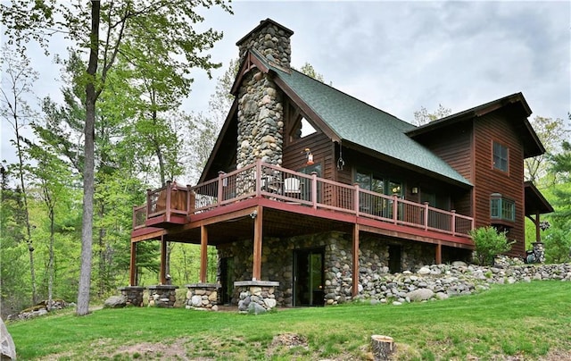10435 W Murphy Blvd, Hayward, WI 54843 - back of house featuring a wooden deck, a lawn, roof with shingles, stone siding, and a chimney
