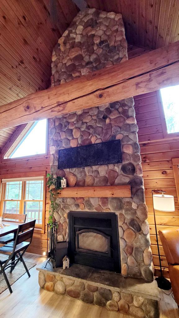 610 Fox Ridge Ct, Nekoosa, WI 54457 - detailed view of a wood ceiling with exposed beams, wood finished floors, a stone fireplace, and wooden walls