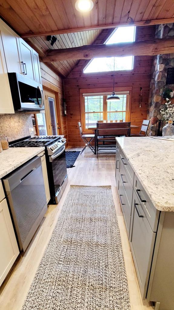 610 Fox Ridge Ct, Nekoosa, WI 54457 - kitchen with wood ceiling, stainless steel appliances, wood walls, light wood finished floors, and light stone counters