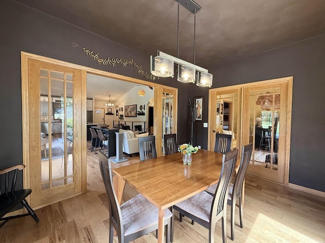 2728 E Ridge Rd, Beloit, WI 53511 - dining space featuring light wood-type flooring, french doors, a chandelier, and baseboards