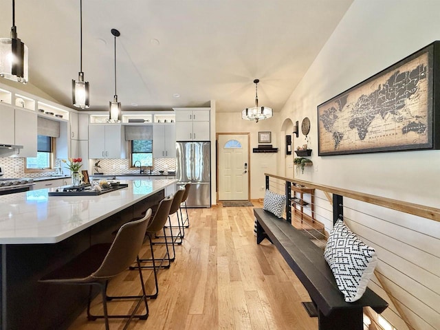 2728 E Ridge Rd, Beloit, WI 53511 - kitchen with appliances with stainless steel finishes, decorative backsplash, a center island, light wood-style flooring, and a chandelier