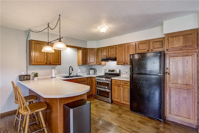 N4907 572nd St, Menomonie, WI 54751 - kitchen featuring double oven range, freestanding refrigerator, a sink, under cabinet range hood, and a peninsula