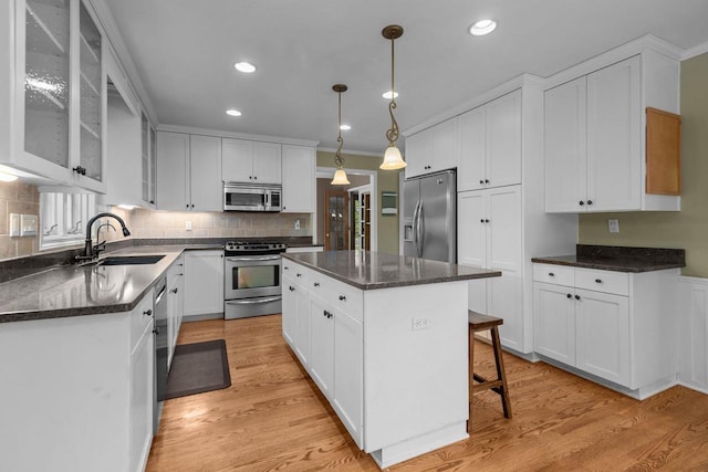 3196 Hidden Pond Rd, Green Bay, WI 54313 - kitchen featuring appliances with stainless steel finishes, a sink, a kitchen island, crown molding, and glass insert cabinets