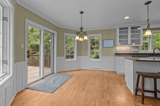 3196 Hidden Pond Rd, Green Bay, WI 54313 - kitchen with a sink, dark countertops, light wood-type flooring, glass insert cabinets, and healthy amount of natural light
