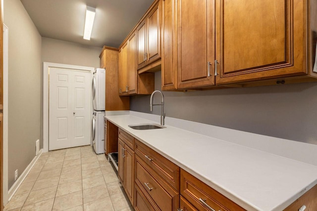845 Lake Rd Unit D, Brookfield, WI 53005 - kitchen with stacked washer / dryer, a sink, brown cabinets, and baseboards