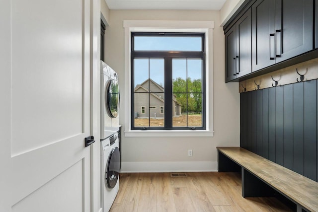 N67W27095 Fanad Dr, Lisbon, WI 53089 - washroom featuring stacked washer and clothes dryer, baseboards, light wood finished floors, and cabinet space