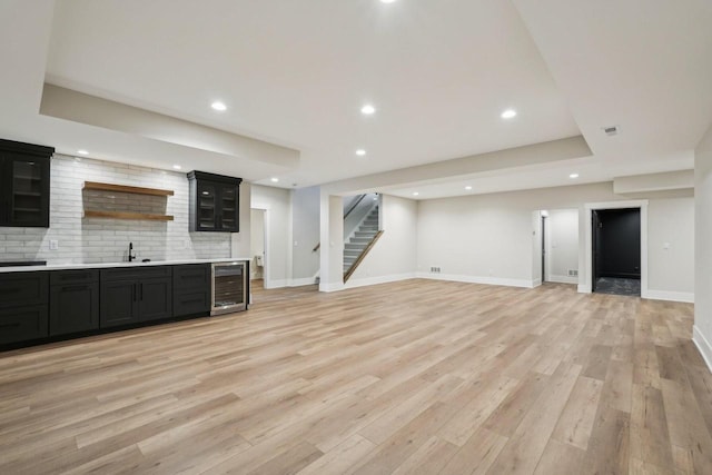 N67W27095 Fanad Dr, Lisbon, WI 53089 - unfurnished living room with wine cooler, stairs, recessed lighting, light wood finished floors, and bar with sink