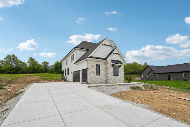 N67W27095 Fanad Dr, Lisbon, WI 53089 - view of front facade featuring an attached garage, concrete driveway, stone siding, and central AC