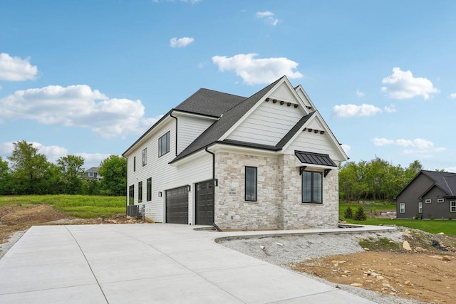 N67W27095 Fanad Dr, Lisbon, WI 53089 - view of front of property featuring stone siding, a garage, cooling unit, and driveway