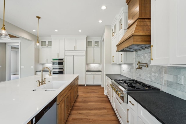 N67W27095 Fanad Dr, Lisbon, WI 53089 - kitchen featuring stainless steel appliances, a sink, custom range hood, white cabinetry, and pendant lighting