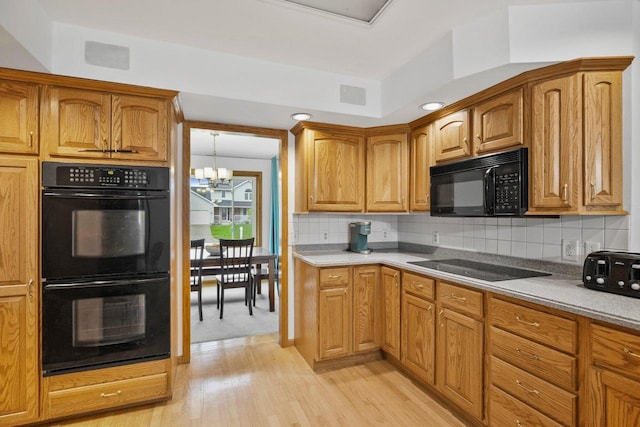 517 Brule Pkwy, Deforest, WI 53532 - kitchen featuring black appliances, a chandelier, tasteful backsplash, and light wood-type flooring
