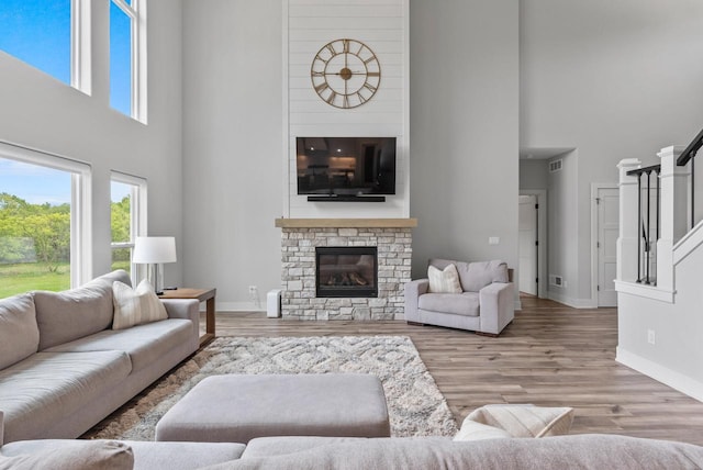 6340 Congress Dr, West Bend, WI 53095 - living area featuring a high ceiling, a stone fireplace, baseboards, and wood finished floors