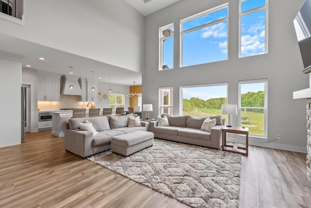 6340 Congress Dr, West Bend, WI 53095 - living room featuring a high ceiling, light wood-style flooring, a stone fireplace, baseboards, and recessed lighting