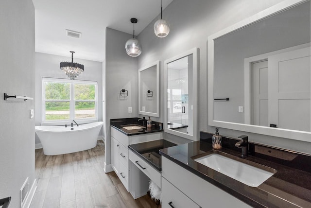 6340 Congress Dr, West Bend, WI 53095 - full bath with two vanities, a freestanding bath, a shower stall, baseboards, and a chandelier