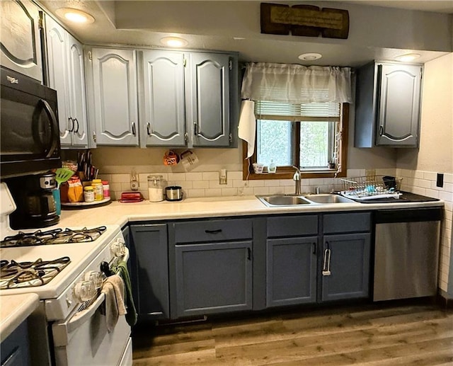 1051 E Chippewa Ave, Bruce, WI 54819 - kitchen with white range with gas stovetop, black microwave, a sink, gray cabinetry, and wood finished floors