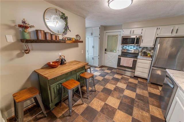 14 Chippewa St, Chippewa Falls, WI 54729 - kitchen with appliances with stainless steel finishes, a textured ceiling, white cabinets, decorative backsplash, and open shelves