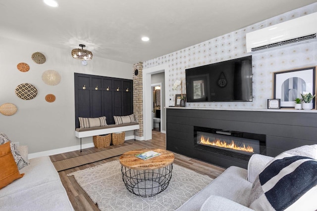 8606 State Highway 57, Baileys Harbor, WI 54202 - living room featuring an AC wall unit, baseboards, wood finished floors, a glass covered fireplace, and wallpapered walls