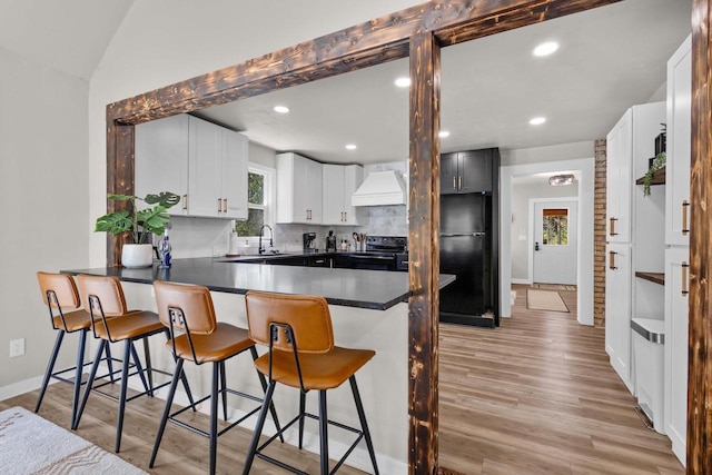 8606 State Highway 57, Baileys Harbor, WI 54202 - kitchen featuring black appliances, premium range hood, a peninsula, decorative backsplash, and baseboards