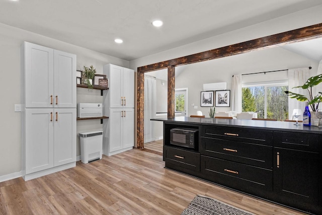 8606 State Highway 57, Baileys Harbor, WI 54202 - kitchen with dark cabinets, open shelves, black microwave, light wood-type flooring, and white cabinets