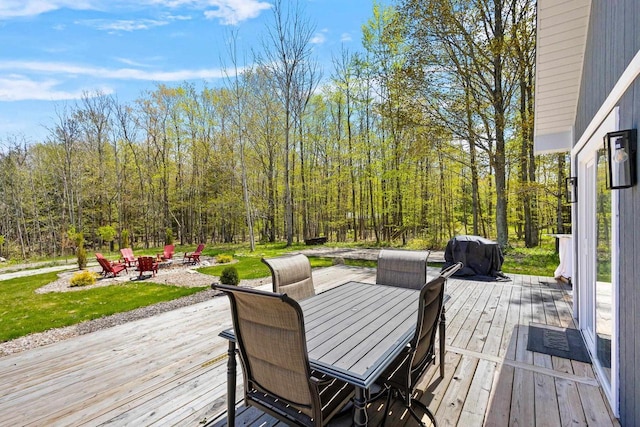 8606 State Highway 57, Baileys Harbor, WI 54202 - wooden terrace featuring an outdoor fire pit, area for grilling, outdoor dining space, a lawn, and a view of trees