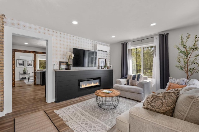 8606 State Highway 57, Baileys Harbor, WI 54202 - living room with a wall mounted air conditioner, wallpapered walls, wood finished floors, a glass covered fireplace, and recessed lighting