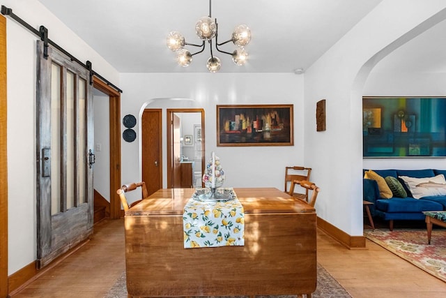 302 River Hts, Shawano, WI 54166 - dining room featuring arched walkways, wood finished floors, a barn door, a chandelier, and baseboards