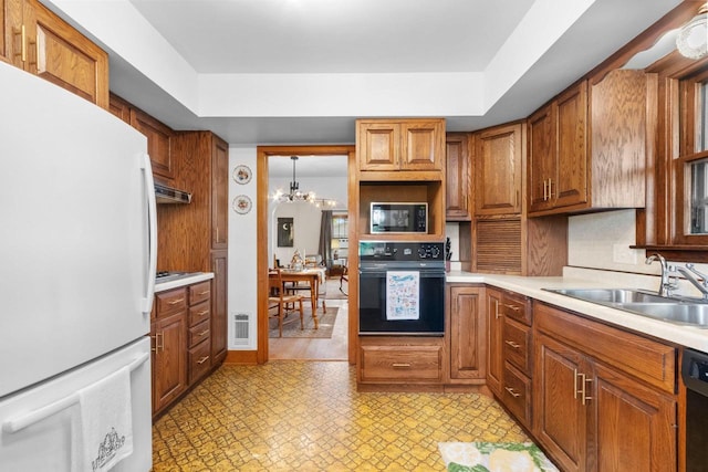302 River Hts, Shawano, WI 54166 - kitchen with black appliances, a sink, light countertops, a chandelier, and brown cabinets