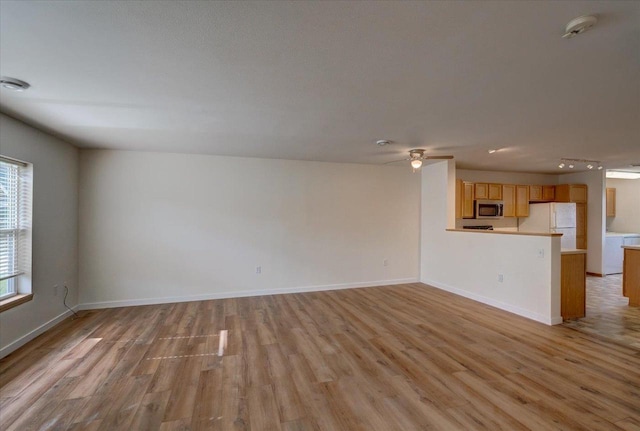 252 S Musket Ridge Dr Unit 2, Sun Prairie, WI 53590 - unfurnished living room featuring light wood-style flooring, a ceiling fan, and baseboards