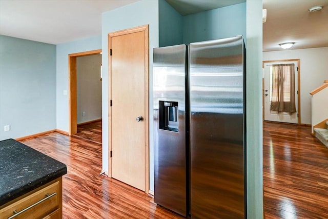 9305 Briar Haven Dr, Verona, WI 53593 - kitchen with stainless steel fridge, wood finished floors, baseboards, and dark stone counters