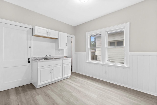 3046 N 57th St, Milwaukee, WI 53210 - kitchen with a sink, light wood-style flooring, wainscoting, white cabinets, and light countertops