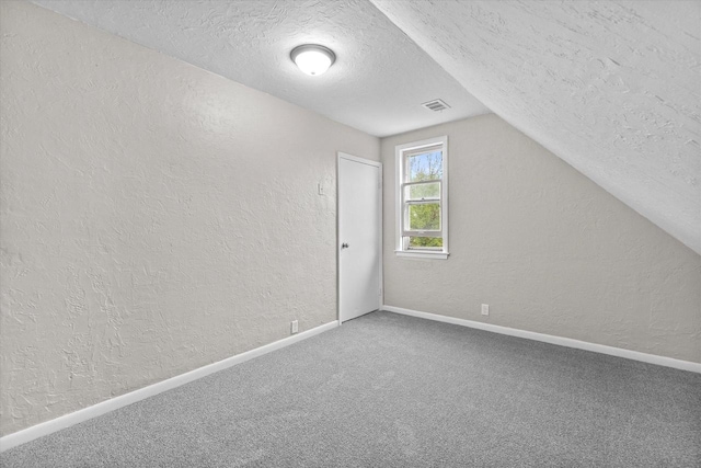 3046 N 57th St, Milwaukee, WI 53210 - bonus room featuring a textured wall, a textured ceiling, lofted ceiling, carpet flooring, and baseboards