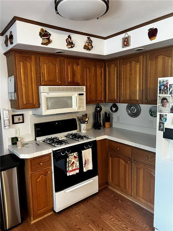 10384 W County Line Rd, Exeland, WI 54835 - kitchen featuring white appliances, ornamental molding, dark wood-type flooring, brown cabinetry, and a textured ceiling