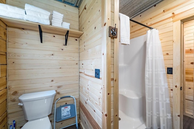 N11594 Woodland Dr, Tomahawk, WI 54487 - bathroom featuring wooden walls, toilet, and a shower with shower curtain
