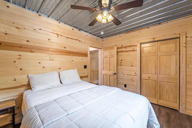 N11594 Woodland Dr, Tomahawk, WI 54487 - bedroom featuring wood walls, dark wood-type flooring, a closet, and a ceiling fan