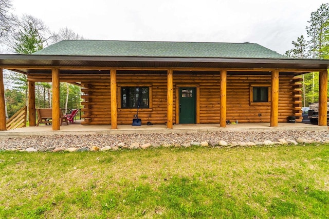 N11594 Woodland Dr, Tomahawk, WI 54487 - view of front of property with log exterior, roof with shingles, a front lawn, and a porch