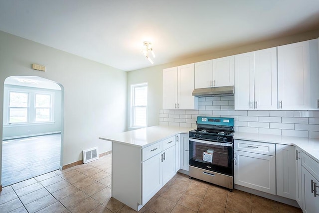 3834 Sheridan Rd, Kenosha, WI 53140 - kitchen featuring gas stove, under cabinet range hood, a peninsula, and decorative backsplash